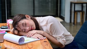 Tired businesswoman sleeping on office desk in front of laptop computer.