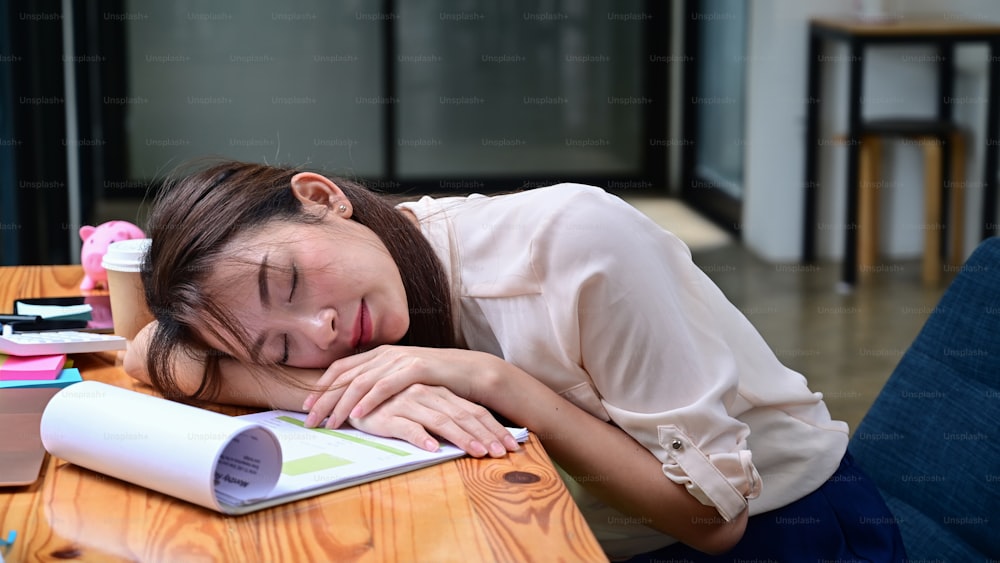 Tired businesswoman sleeping on office desk in front of laptop computer.