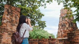 Donna asiatica viaggiatrice che utilizza la macchina fotografica per scattare una foto mentre trascorre il viaggio di vacanza ad Ayutthaya, Thailandia, turista giapponese si gode il suo viaggio in un incredibile punto di riferimento nella città tradizionale.