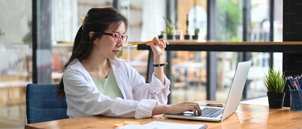 Businesswoman talking on speaker phone and working with computer laptop in office.