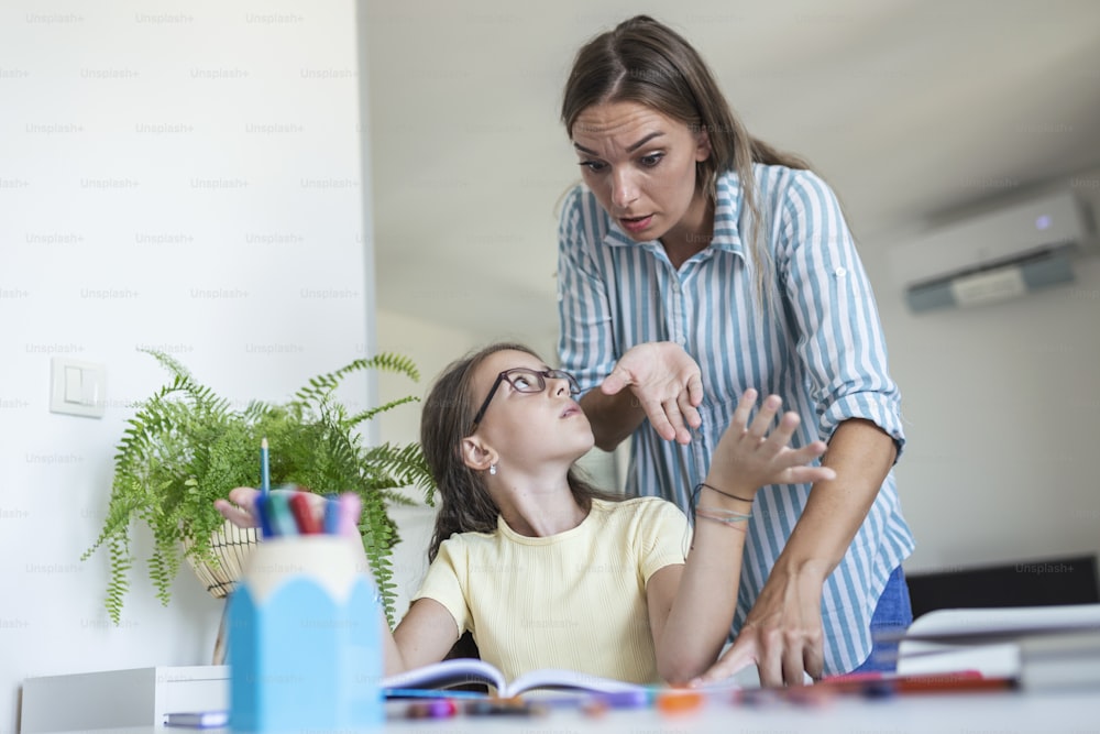 Stressed mother and son frustrated over failure homework, school problems concept. Sad little girl turned away from mother, does not want to do boring homework