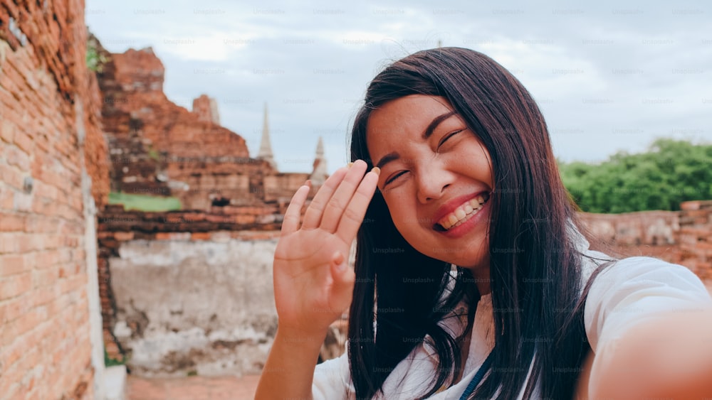 クローズアップ若いアジアのバックパッカーブロガーの女性のカジュアルなルックカメラのビデオ通話スマートフォンで共有パゴダ旧市街で一緒に視聴者の旅行のためにオンラインでライブ共有、ライフスタイルの観光旅行の休日のコンセプト。