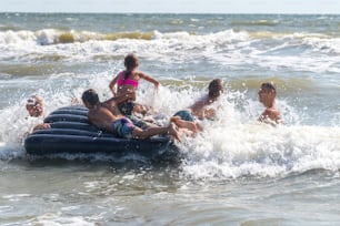 Familia alegre y feliz de vacaciones a la orilla del mar. Padre y abuelo jugando con niños en las olas del mar. Viajes de verano y vacaciones al aire libre, estilo de vida saludable