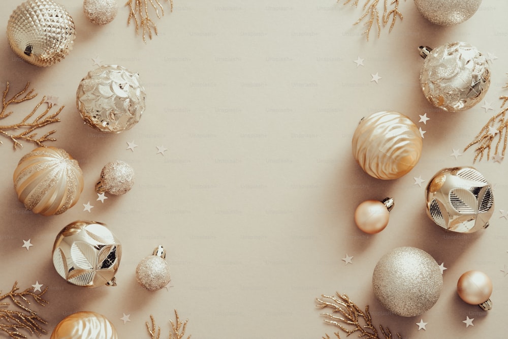 Composition de Noël. Cadre composé de décorations de boules dorées sur fond beige pastel. Concept de Noël, hiver, nouvel an. Pose à plat, vue de dessus