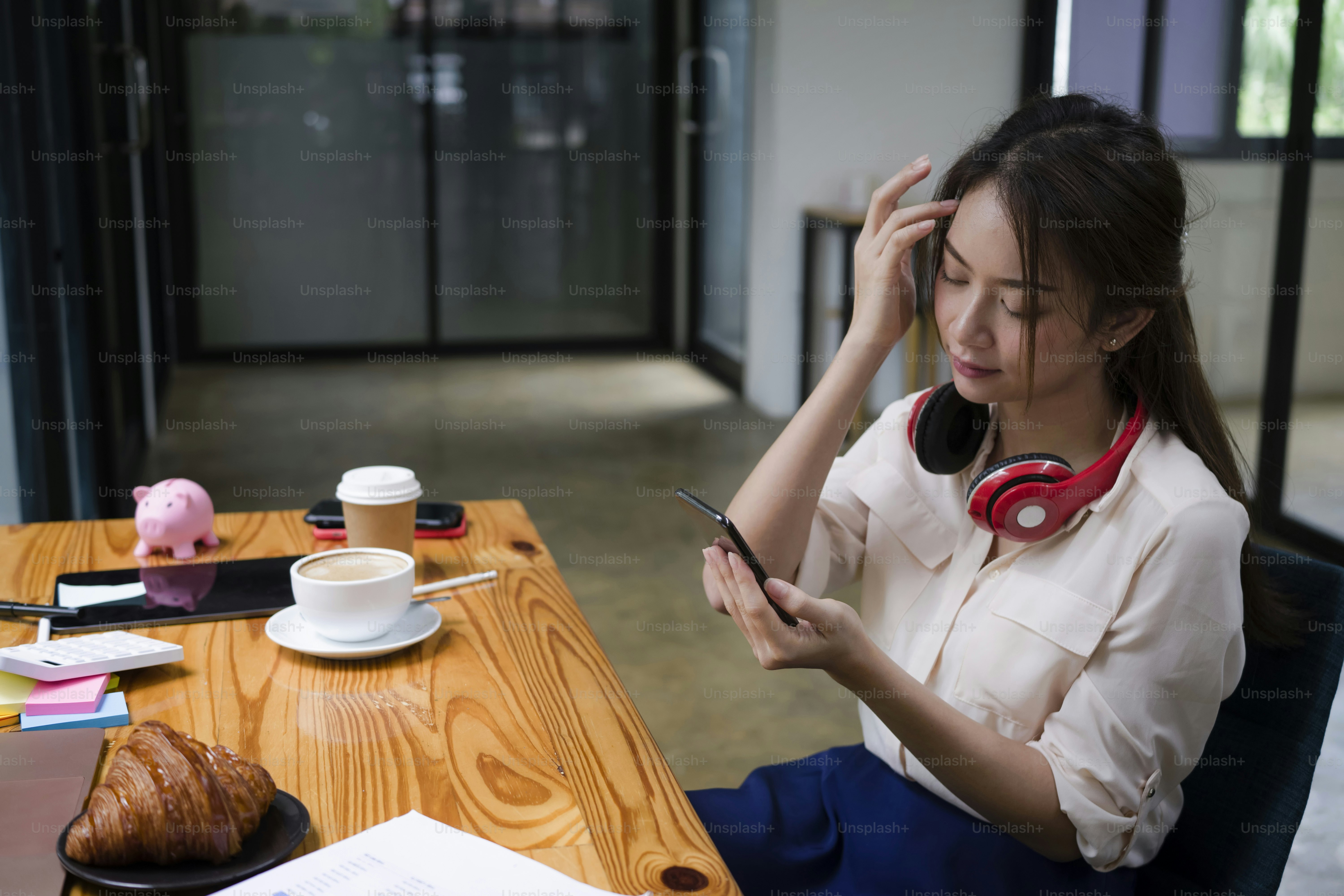 Young female office worker sitting at her office desk and using smart phone.