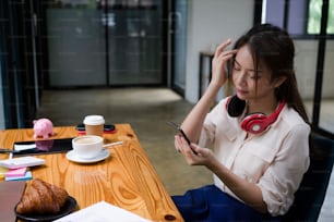 Young female office worker sitting at her office desk and using smart phone.