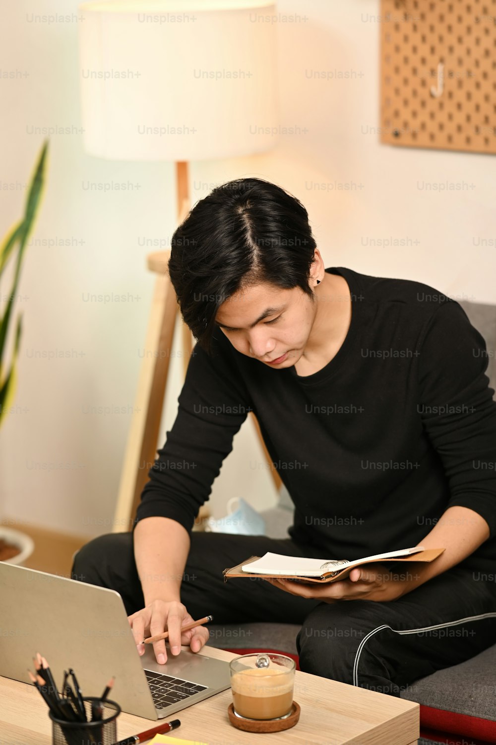 Young Asian man sitting on couch and using laptop.