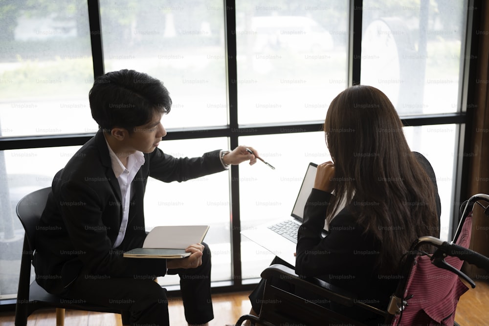 Disabled businesswoman working with her colleague in modern workplace.