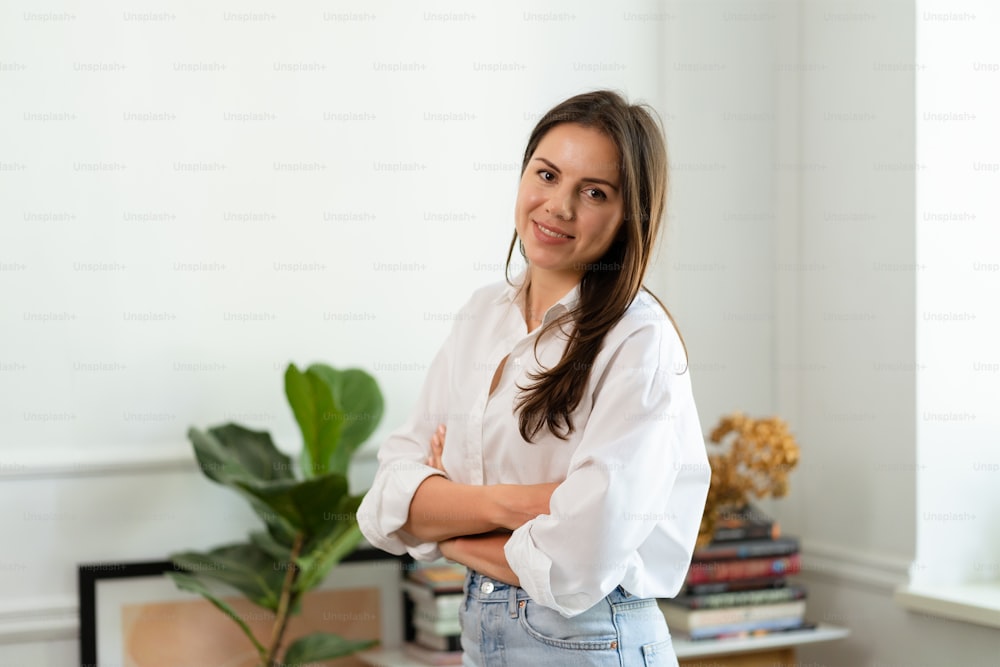 Image of young cheery positive beautiful business woman sitting indoors in office or home office using laptop computer.