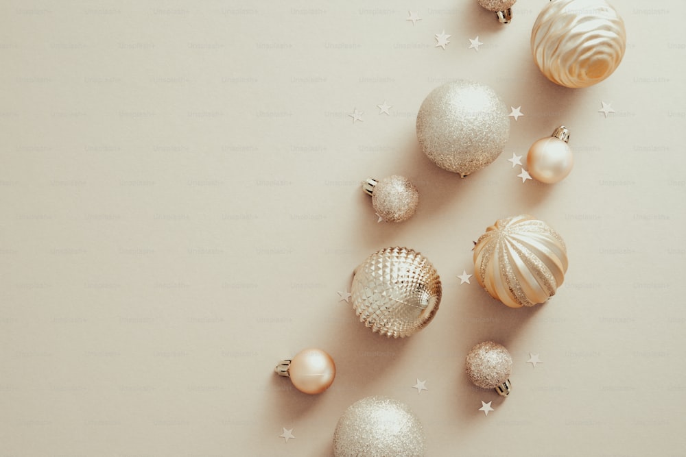 Christmas and New Year holidays concept with golden balls decorations on pastel beige background. Top view, flat lay. Minimal style.