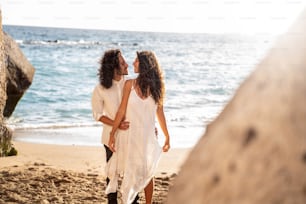 Feliz pareja enamorada relajándose en la playa tropical, disfrutando de la luna de miel y las vacaciones de verano. Mujer y hombre mirándose. Personas reales, estilo de vida y emociones.