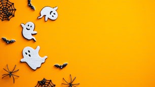 Halloween background with ghosts, bats, spiders, decorations. Halloween party invitation card mockup. Flat lay, top view, copy space.