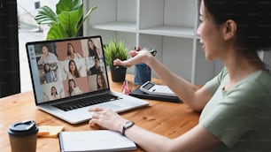 Young Asian woman having video conference with her colleagues on laptop computer.