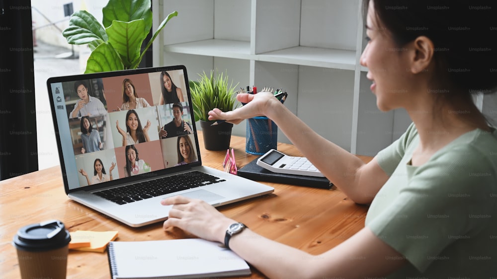Jeune femme asiatique ayant une vidéoconférence avec ses collègues sur un ordinateur portable.