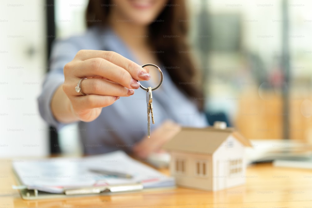 Female residential broker, real estate agent holding house keys in hand, property investment concept