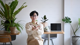 Young Asian man small business entrepreneur holding potted plant and smiling to camera.