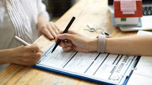 Mãos em close-up de corretora de imóveis feminina e cliente segurando caneta para assinar sua assinatura no contrato de aluguel de casa. Feche o negócio, acordo