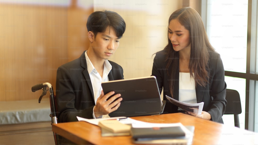 Asian female business manager coaching her new disabled person in wheelchair. businessman in wheelchair. physical disability