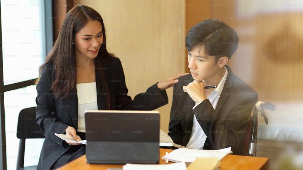 Female manager encourage her disabled employee and work together. Businessman in wheelchair