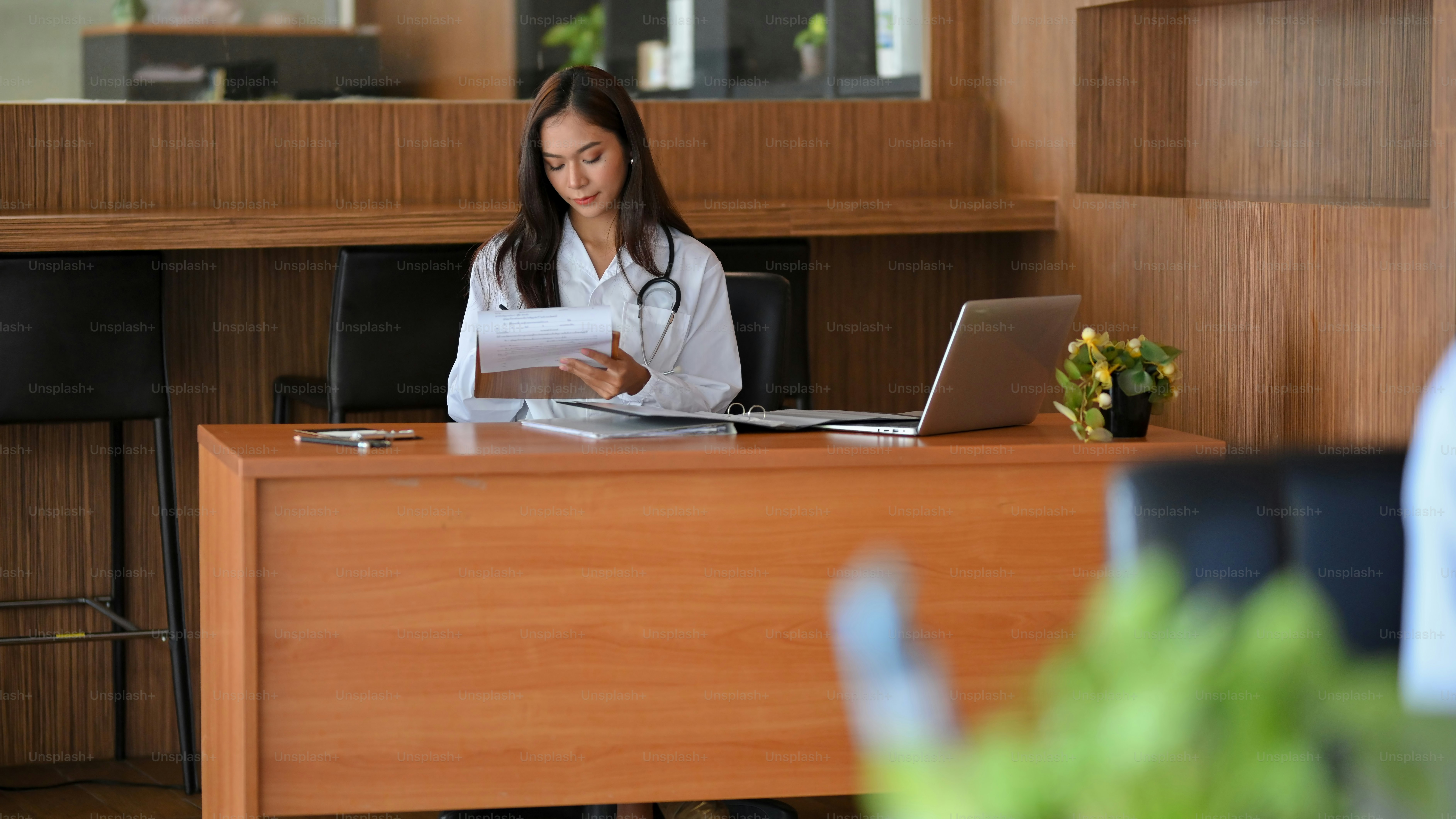 Female doctor, pharmacist or therapist working at her desk at hospital, writing medicine prescriptions