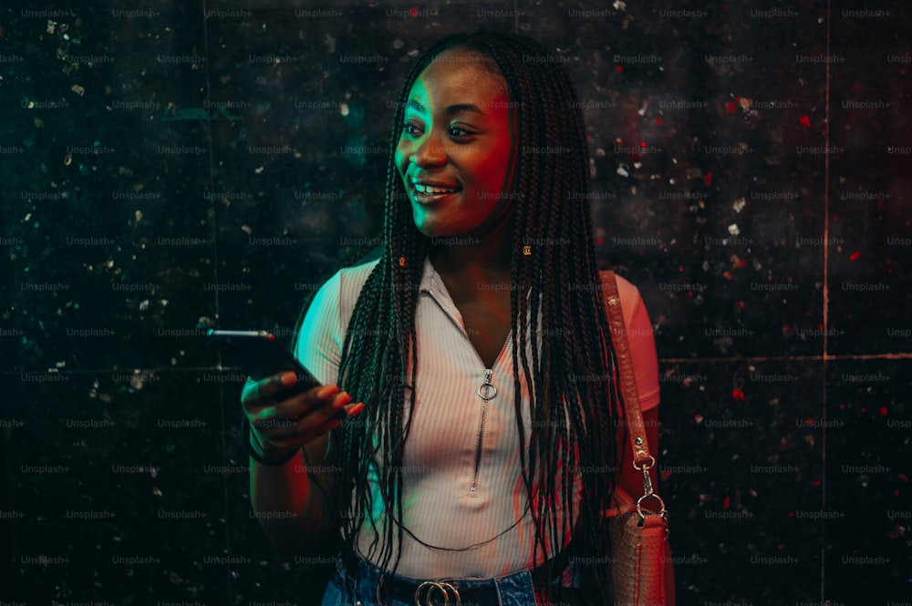 Beautiful young african american woman using smartphone while out in the city during night