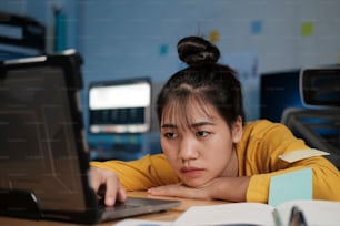 Stressed exhausted woman sitting at office desk and working overtime, she is overloaded with work.