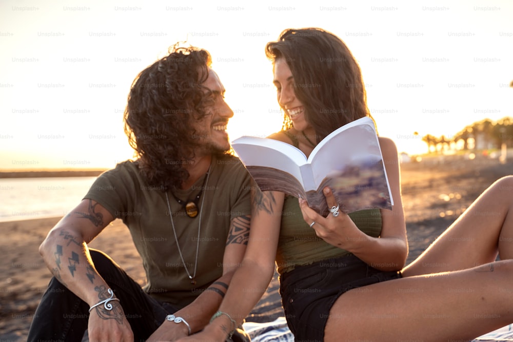 Schönes glückliches Paar bei einem Date, ein Buch am tropischen Strand lesend. Sommerferien-Vibes. Sonnenuntergangszeit.