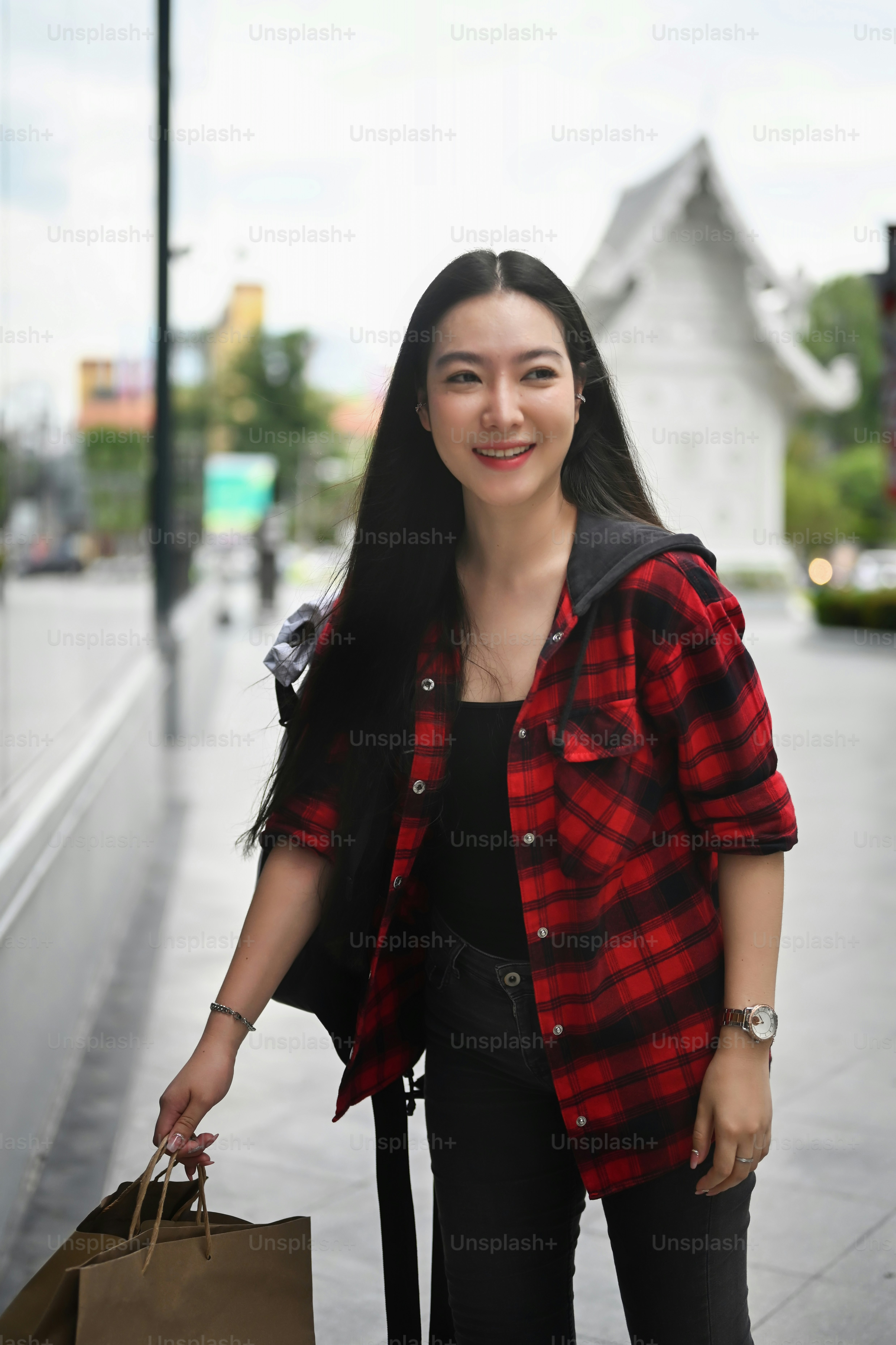 Portrait smiling young woman carrying shopping bags and walking in city street.