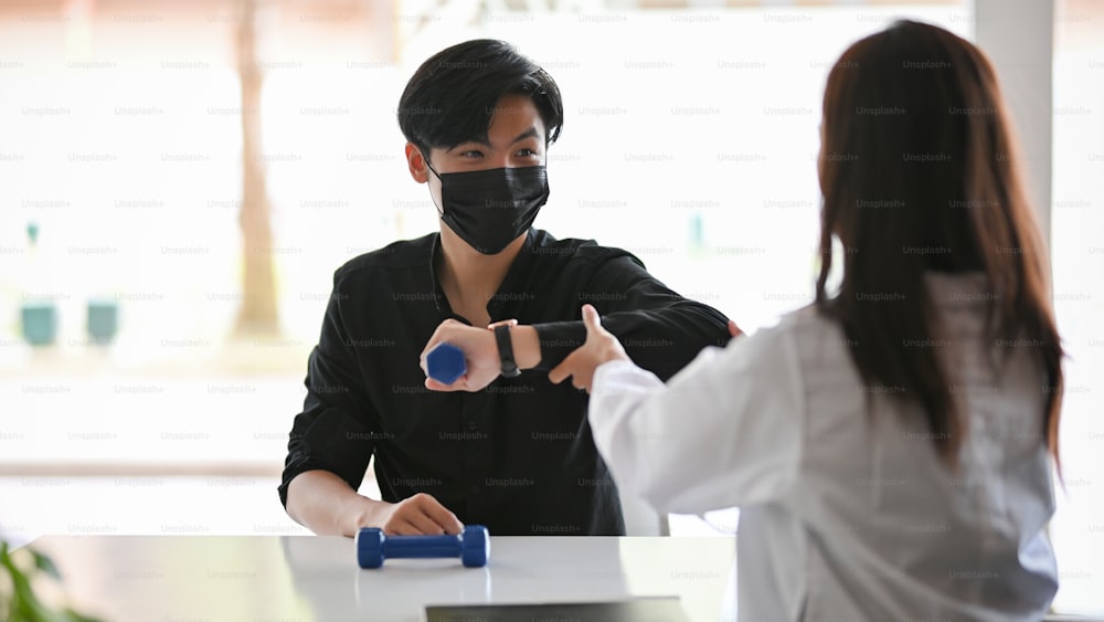 Young handsome man wearing face mask has an appointment with his therapist for a medical therapy at clinic