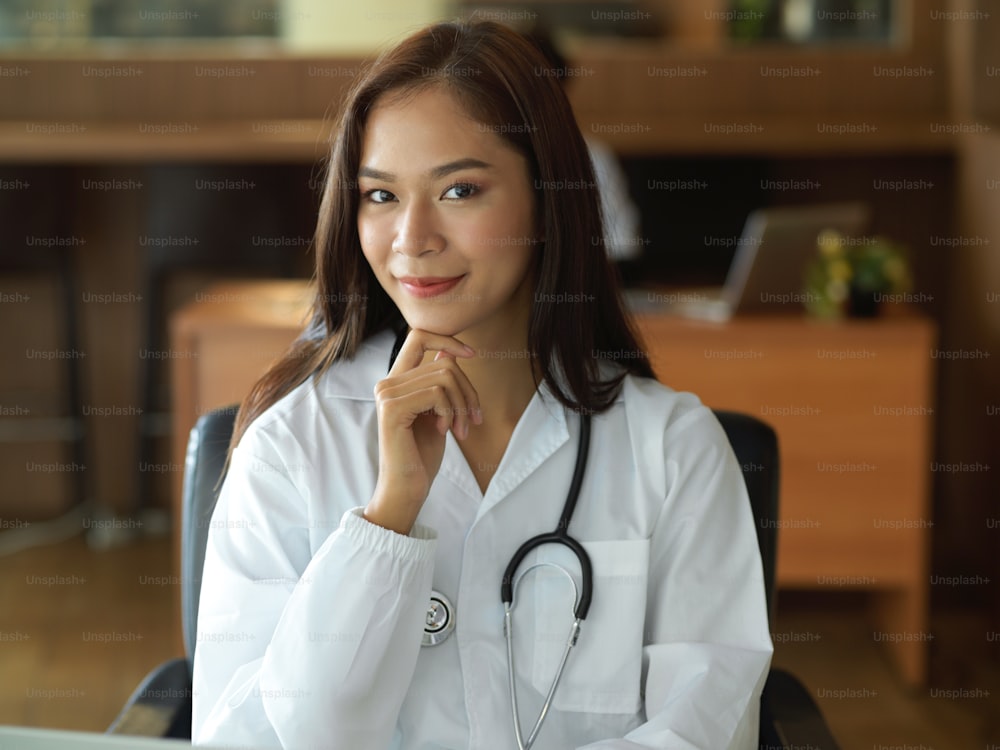 사무실에서 청진기를 가진 흰 가운을 입은 아시아의 젊은 여성 의사