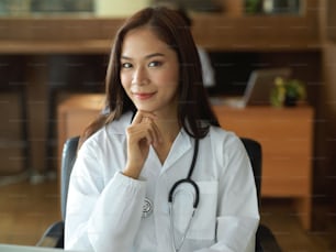 Asian young female doctor in white gown with stethoscope in office