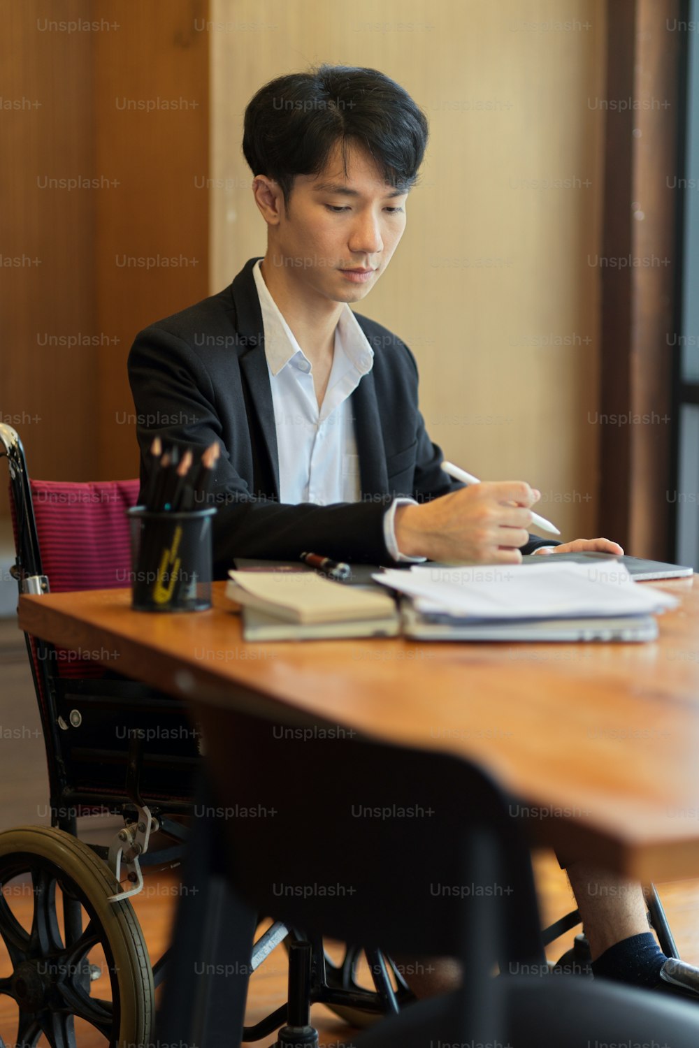 Portrait of young asian businessman in wheelchair in office. disabled employee