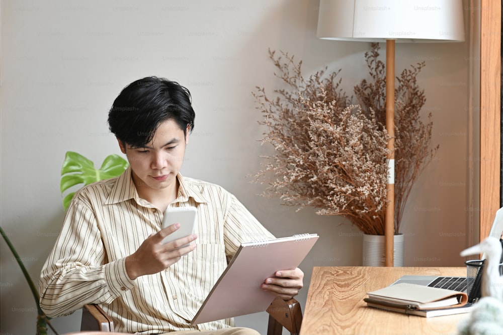Kleinunternehmer, der mit einem digitalen Tablet arbeitet und ein Smartphone verwendet.