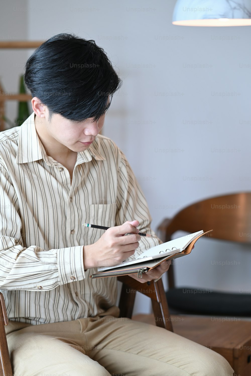 Portrait of handsome businessman holding pen and writing information on notebook.