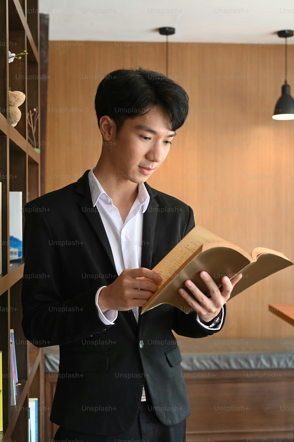 Hombre de negocios inteligente leyendo un libro mientras está de pie en una oficina moderna.