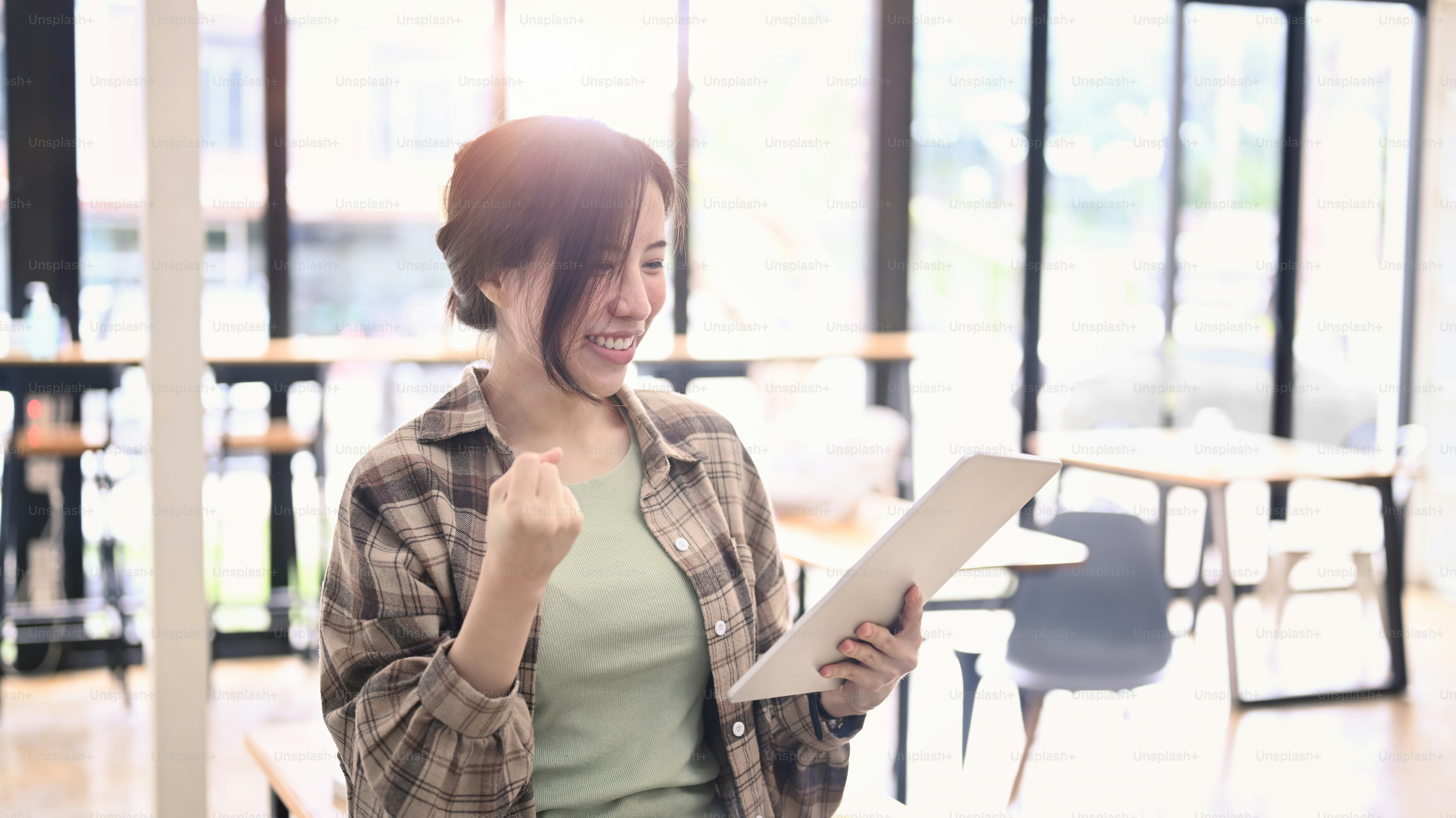 Excited young woman reading good news on digital tablet and celebrating success.