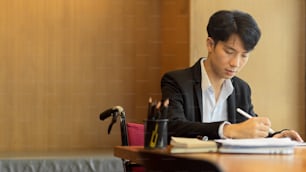 Young asian businessman in wheelchair working in office
