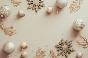 Quadro de Natal com flocos de neve dourados, galhos da árvore de Natal, bolas no fundo bege. Flat lay, vista superior.