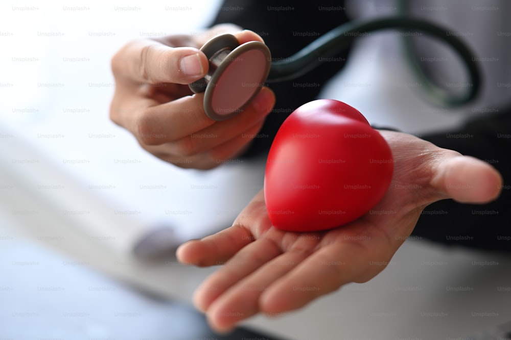 Primer plano médico sosteniendo corazón rojo y estetoscopio. Concepto de seguro de salud
