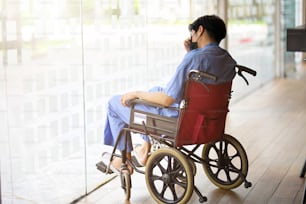 Depressed handicapped male patient in wheelchair looking out through the window, paraplegic, disabled man