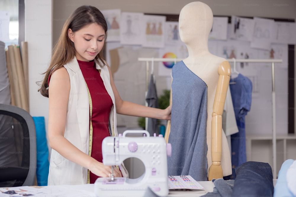 A model is used by a fashion designer to try on new designer garments. At work, a woman entrepreneur in her fabric business is designing new clothing for a fashion designer.
