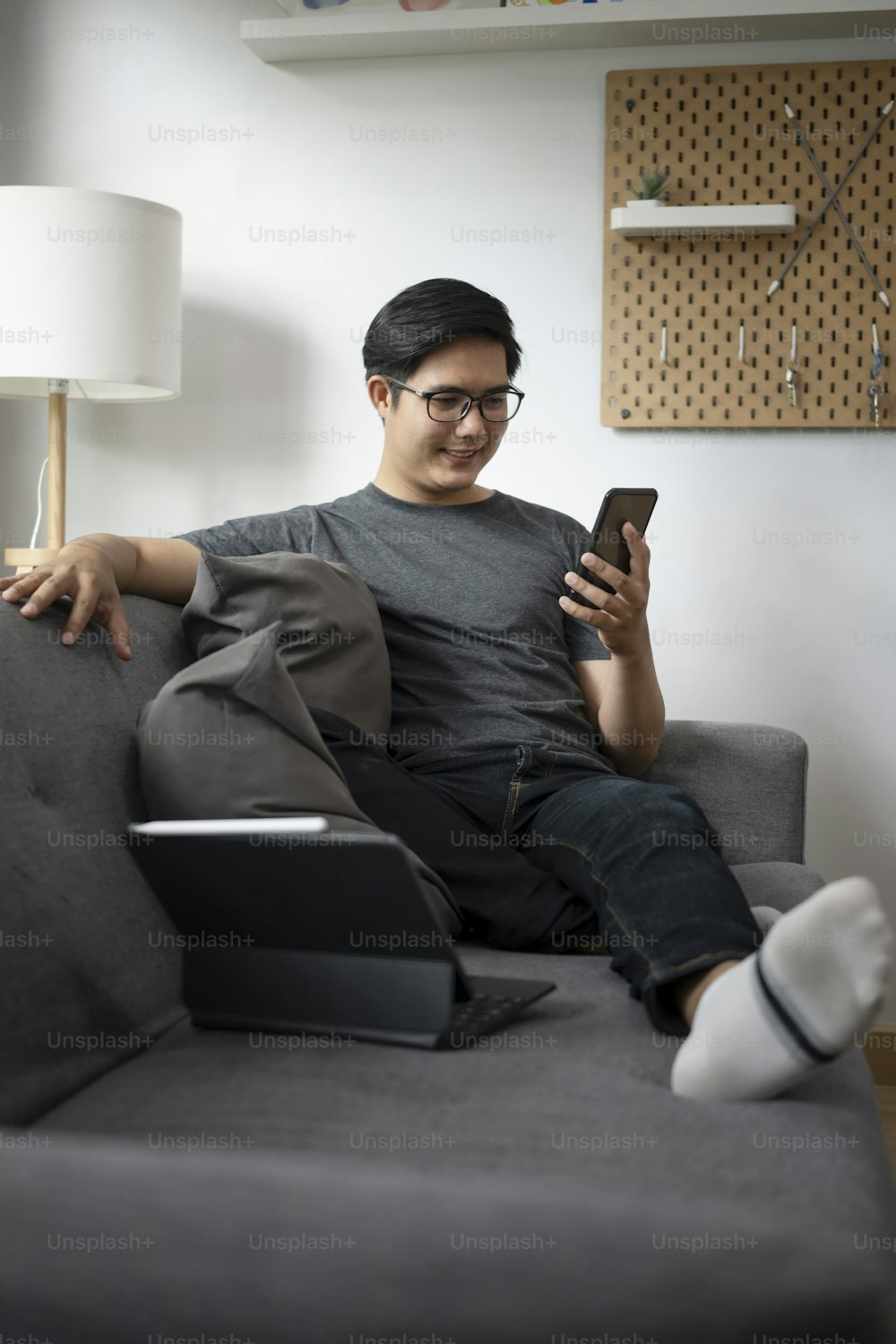 Happy man using smart phone while sitting on comfortable couch in living room.