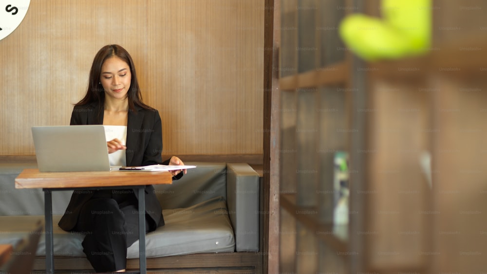 Gerente feminino elegante que trabalha no laptop no café. Executiva de contas profissional senta-se no café à espera de reunião de negócios com clientes