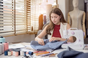 A model is used by a fashion designer to try on new designer garments. At work, a woman entrepreneur in her fabric business is designing new clothing for a fashion designer.