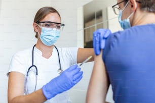 General practitioner vaccinating old patient in clinic with copy space. Doctor giving injection to senior man at hospital. Nurse holding syringe before giving Covid-19 or coronavirus vaccine.