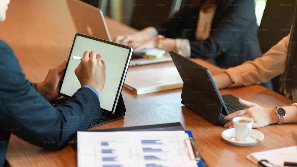 Imagem recortada de empresários tendo reunião e brainstorming na sala de reuniões, trabalhando em tecnologia sem fio, tela em branco do tablet
