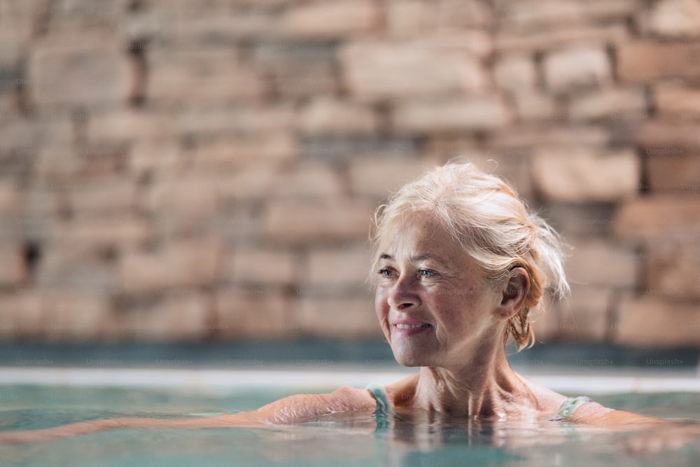 실내 수영장, 수영에서 행복한 노인 여성의 초상화.
