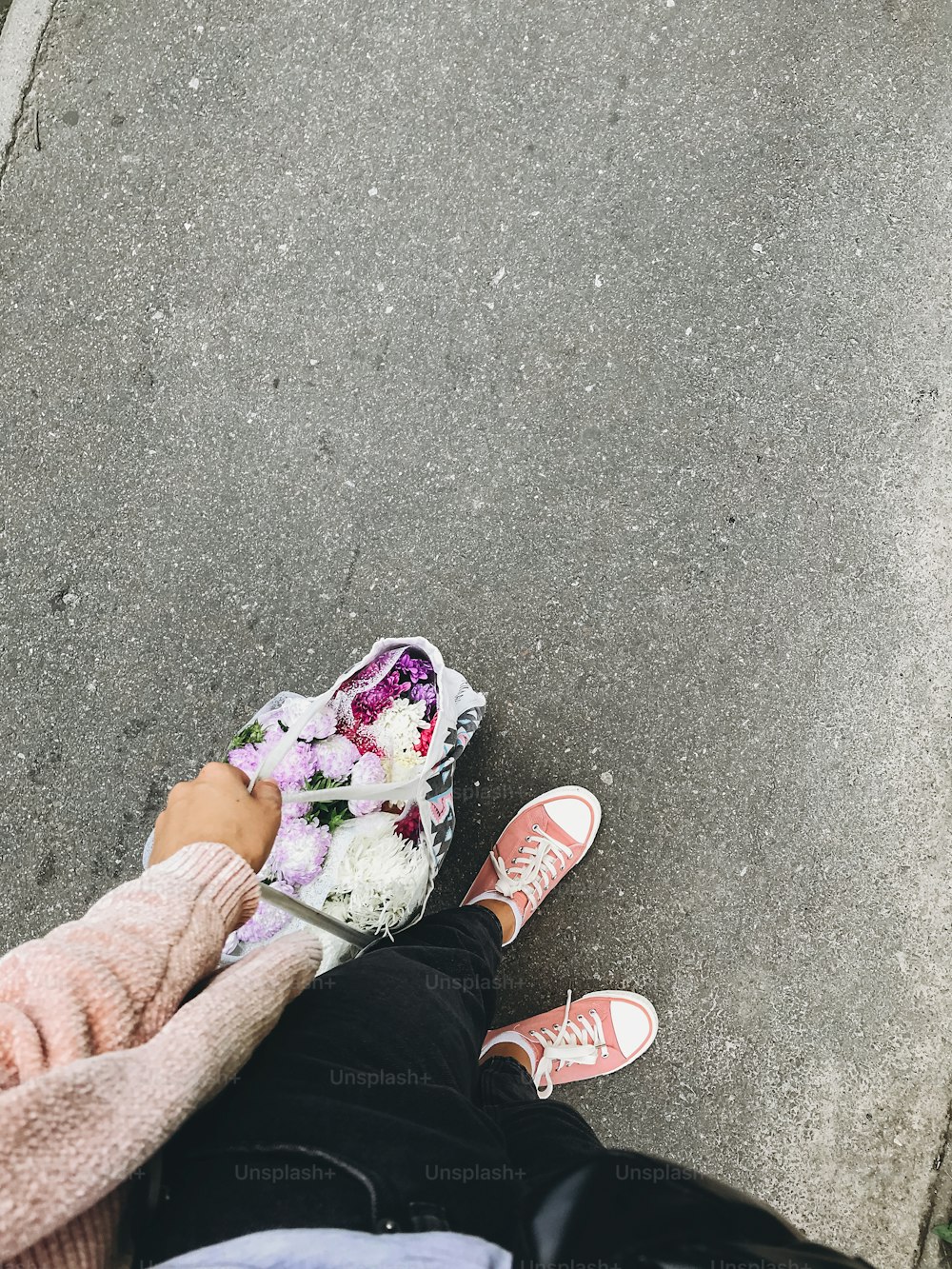 Top view of stylish hipster woman holding bag with bunch of autumn flowers. Hello autumn concept, buying flowers in reusable bag. Female legs in pink sneakers