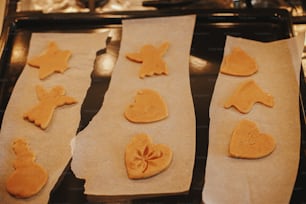 Délicieux biscuits en pain d’épices sur papier sur plateau en gros plan. Cuisson de biscuits de Noël. Préparation des fêtes, culinaire de Noël. Recette de biscuits