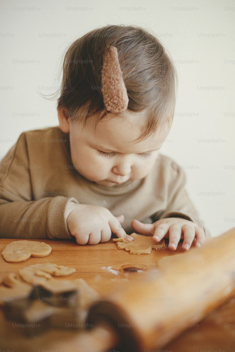 散らかったテーブルでクリスマスクッキーを作るかわいい女の子、接写。母親を助け、ジンジャーブレッドクッキーの生地を切る愛らしい幼児の娘。素敵なひととき、休日の準備